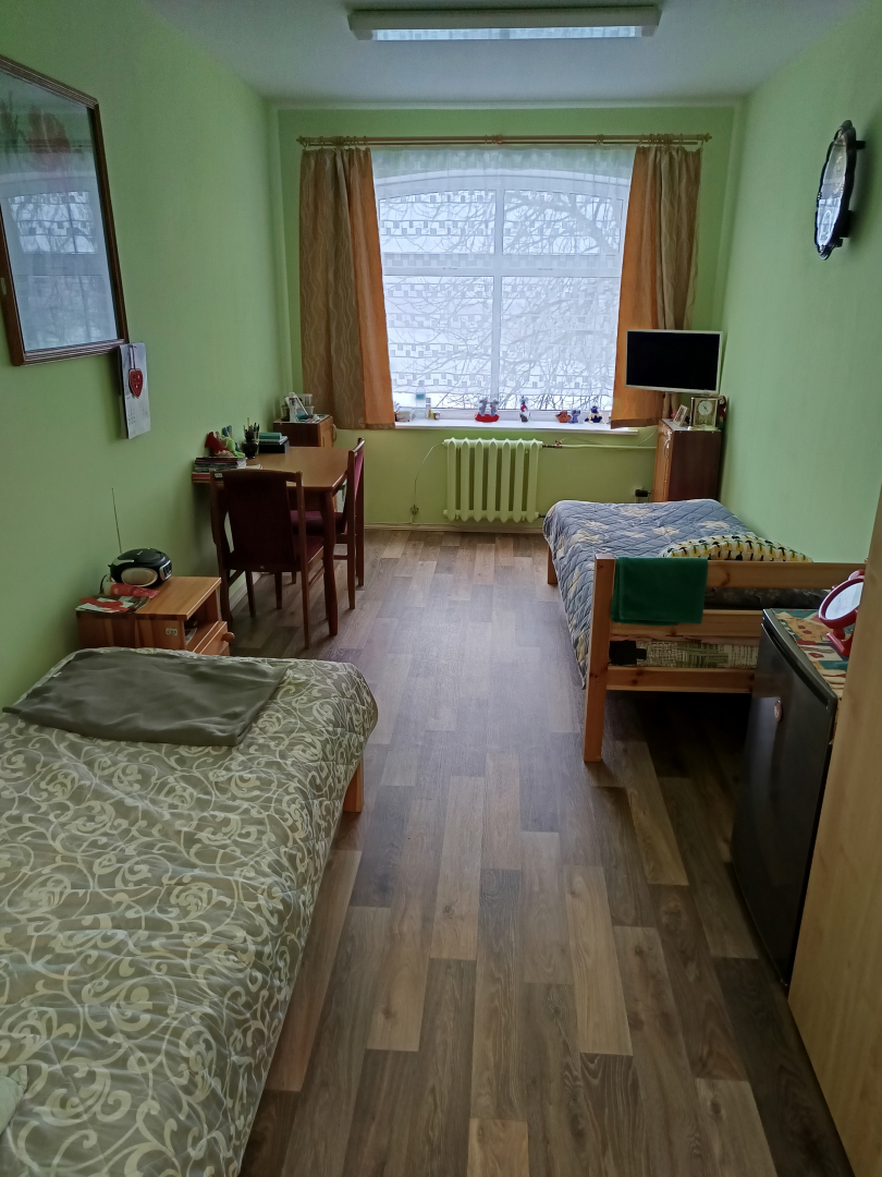 Iedzīvotāju istaba pēc remonta veikšanas, gaiši zaļas sienas, brūns grīdas segums, mēbeles