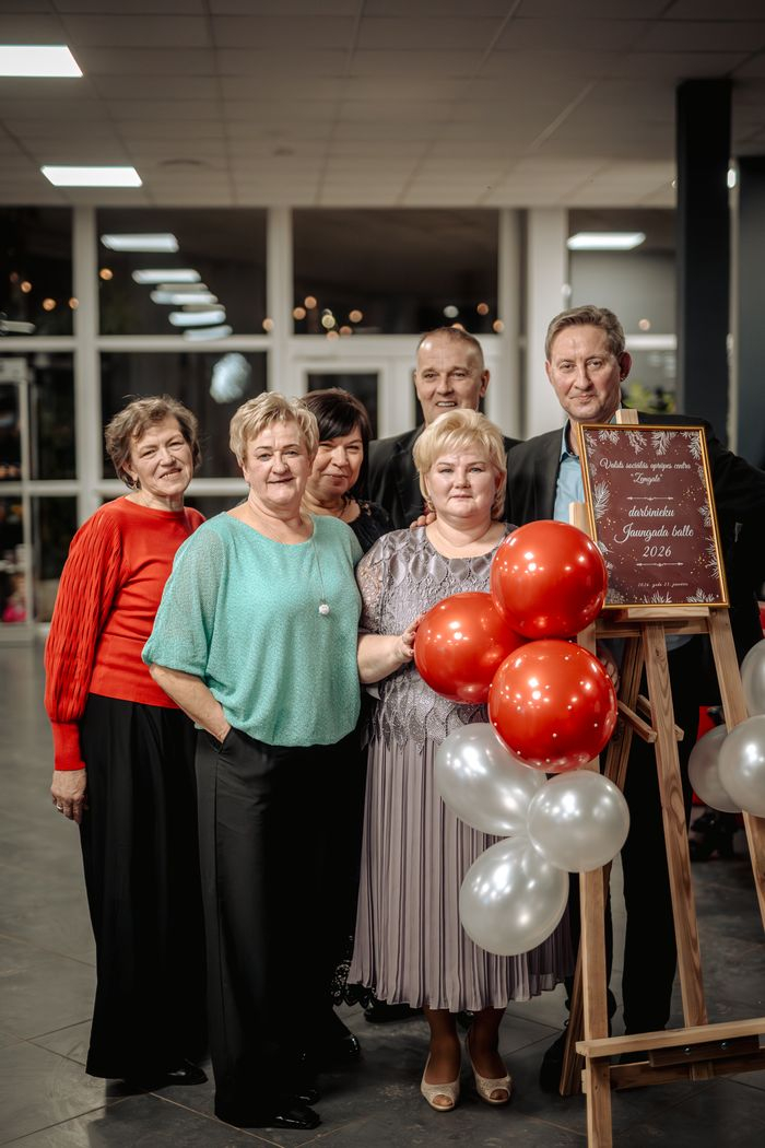 Iestādes darbinieki fotografējas pie sarkaniem un baltiem baloniem