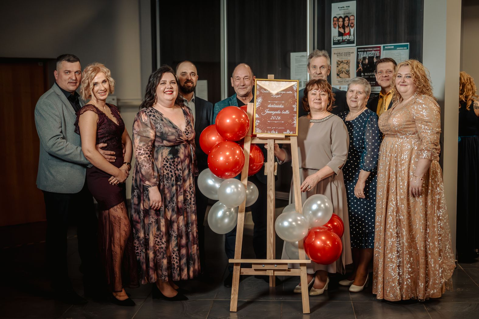 Iestādes darbinieki fotografējas pie sarkaniem un baltiem baloniem