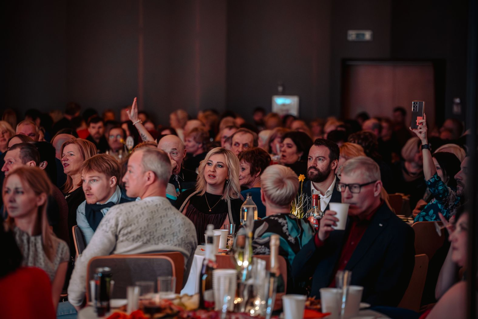 Pasākuma dalībnieki sēž pie galdiem