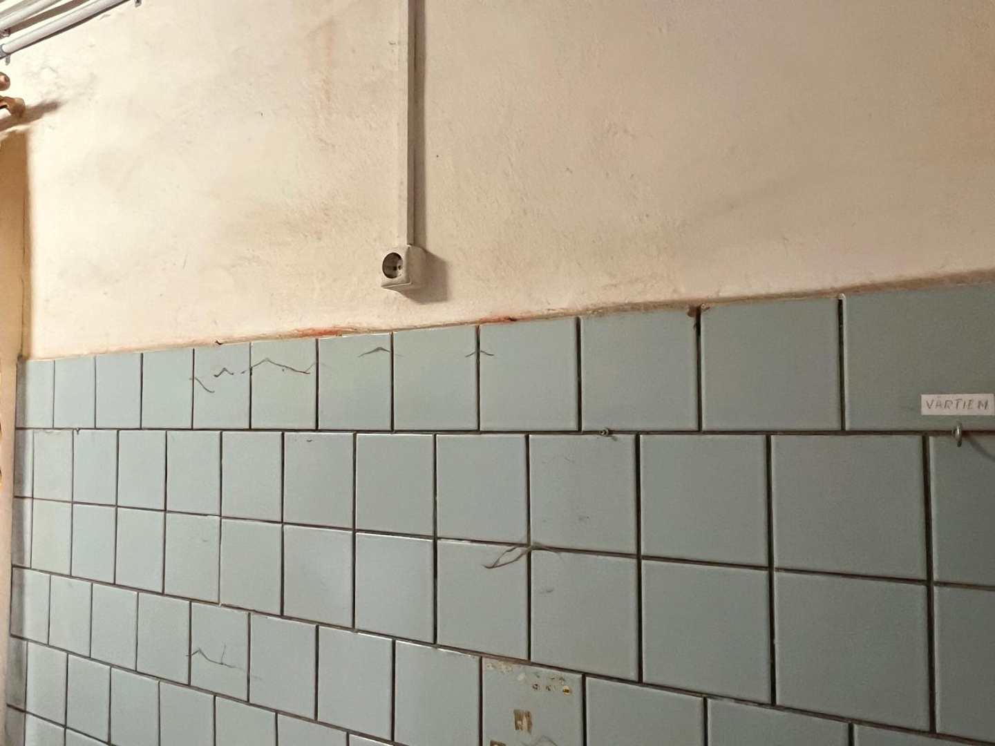 Telpa pirms remonta veikšanas. Netīras sienas blāvi zilas flīzes.