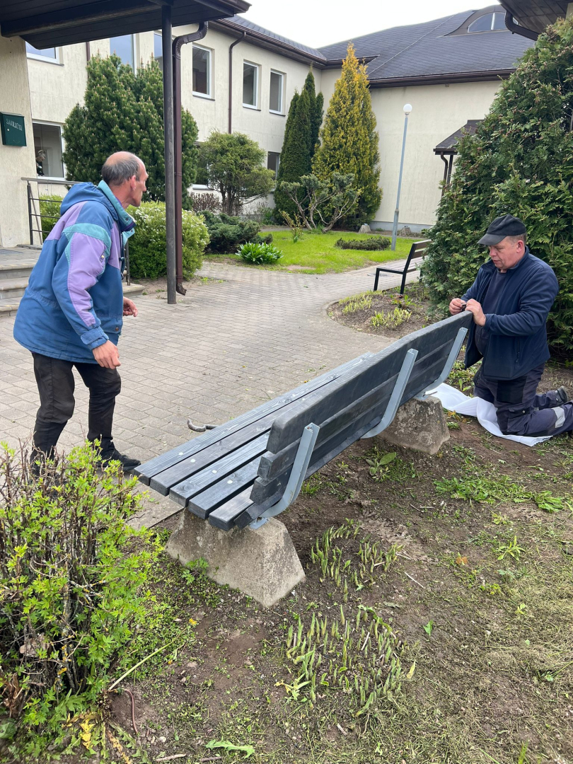 Filiāles "Rūja" darbinieks un iedzīvotājs fotogrāfijā pie atjaunotā sola