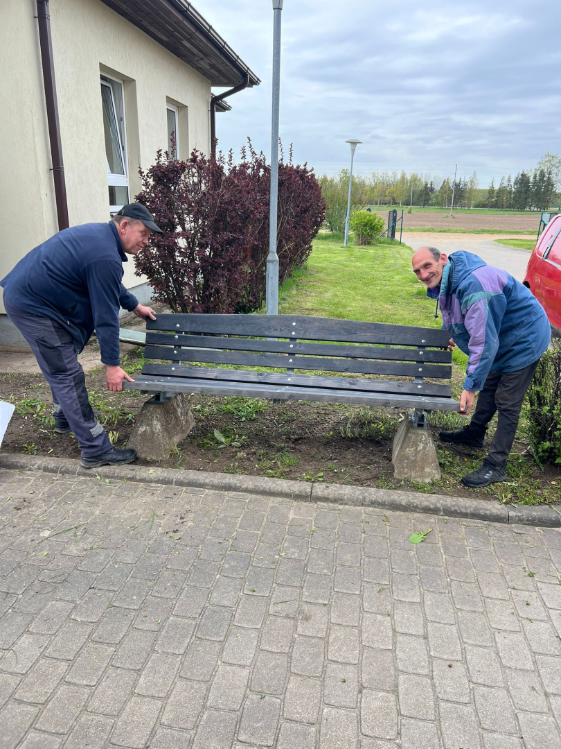 Filiāles "Rūja" darbinieks un iedzīvotājs fotogrāfijā pie atjaunotā sola