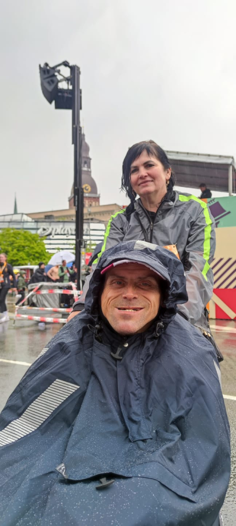 Maratona dalībnieks ratiņkrēslā ar darbinieci pirms distances veikšanas