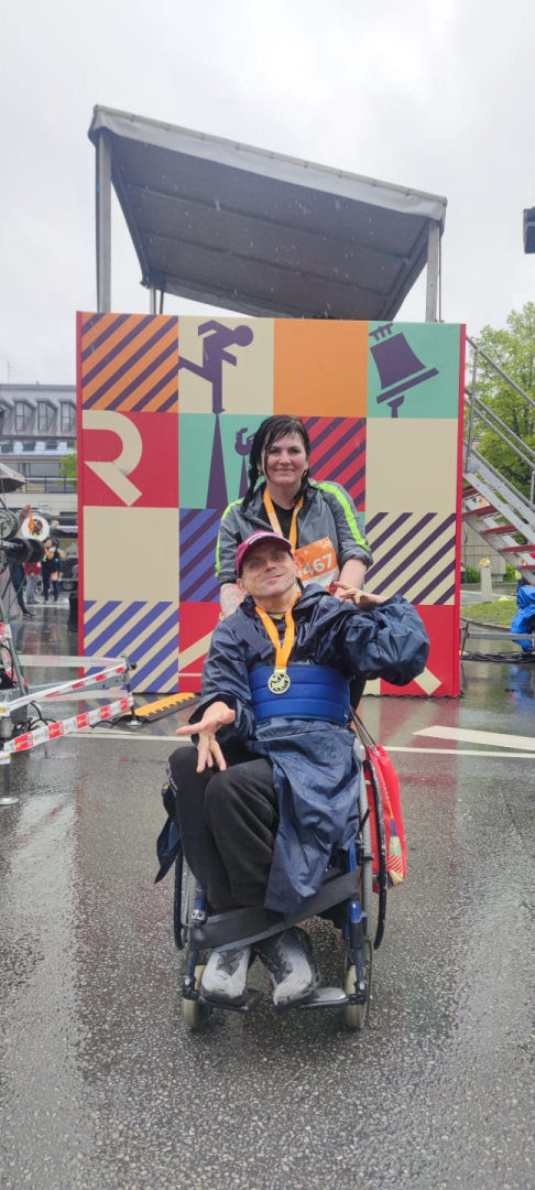 Maratona dalībnieks ratiņkrēslā ar darbinieci pēc distances veikšanas