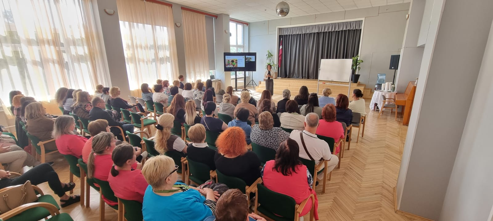 Zāle pilna ar dalībniekiem, kuri klausās runātājā