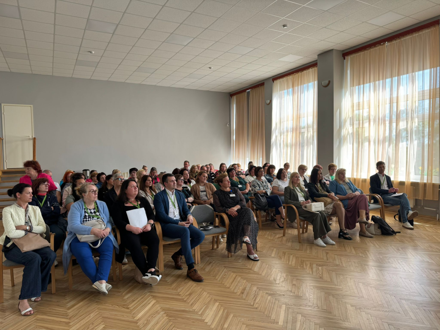 Zāle pilna ar dalībniekiem, kuri klausās runātājā