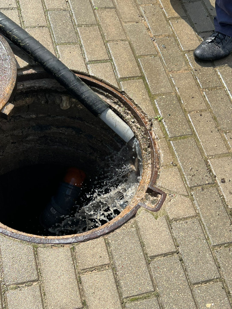 Attēlā āra kanalizācijas lūka, kurā tiek liets ūdens