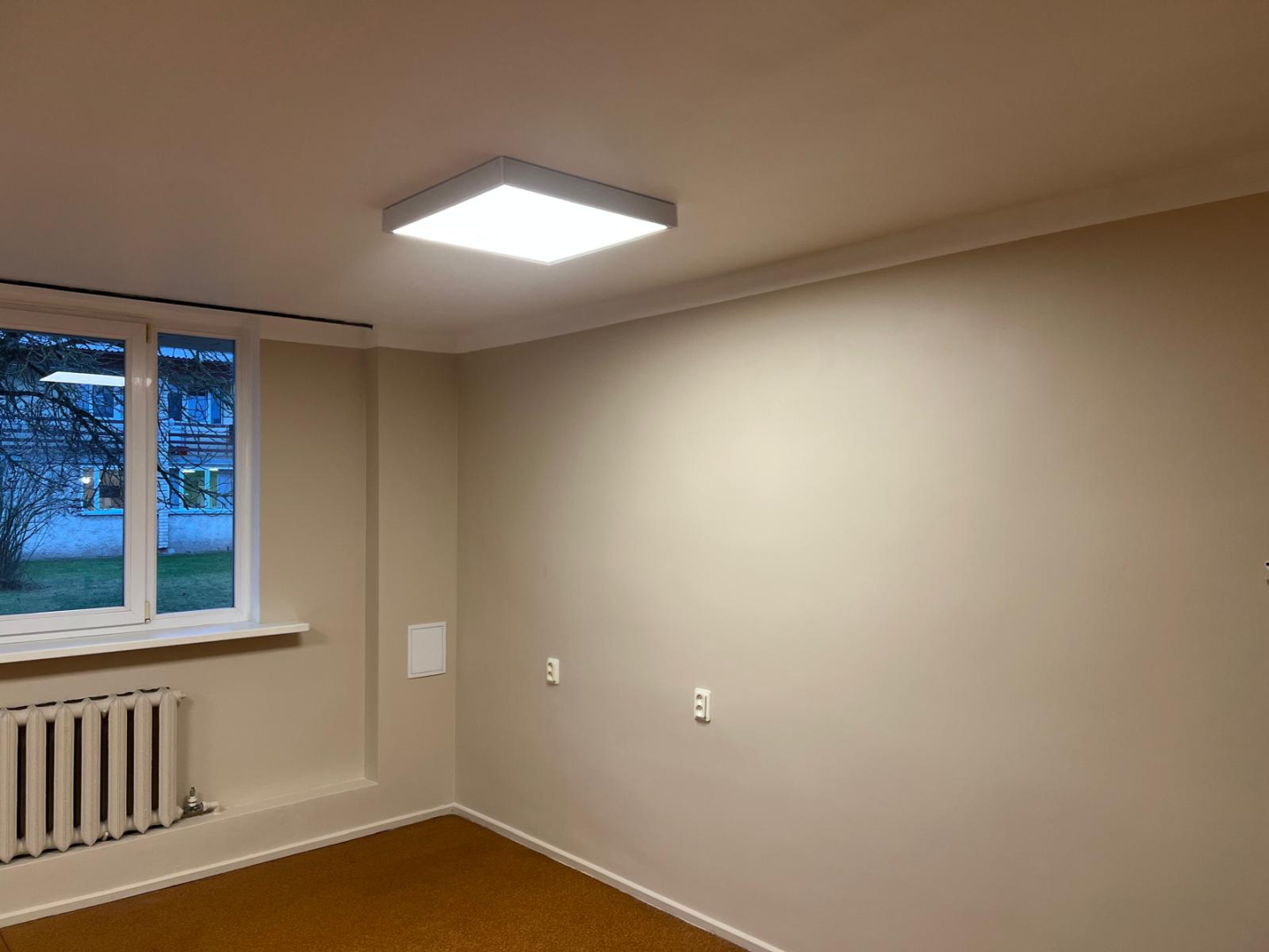 Telpa pēc remonta veikšanas. Gaišas nokrāsotas sienas bēšā krāsā. Jauna grīda, kantainas lampas pie griestiem.