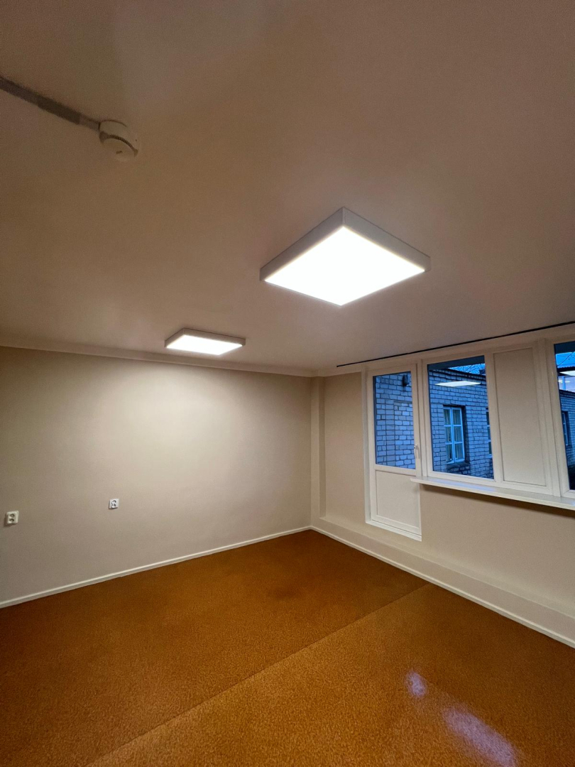 Telpa pēc remonta veikšanas. Gaišas nokrāsotas sienas bēšā krāsā. Jauna grīda, kantainas lampas pie griestiem.