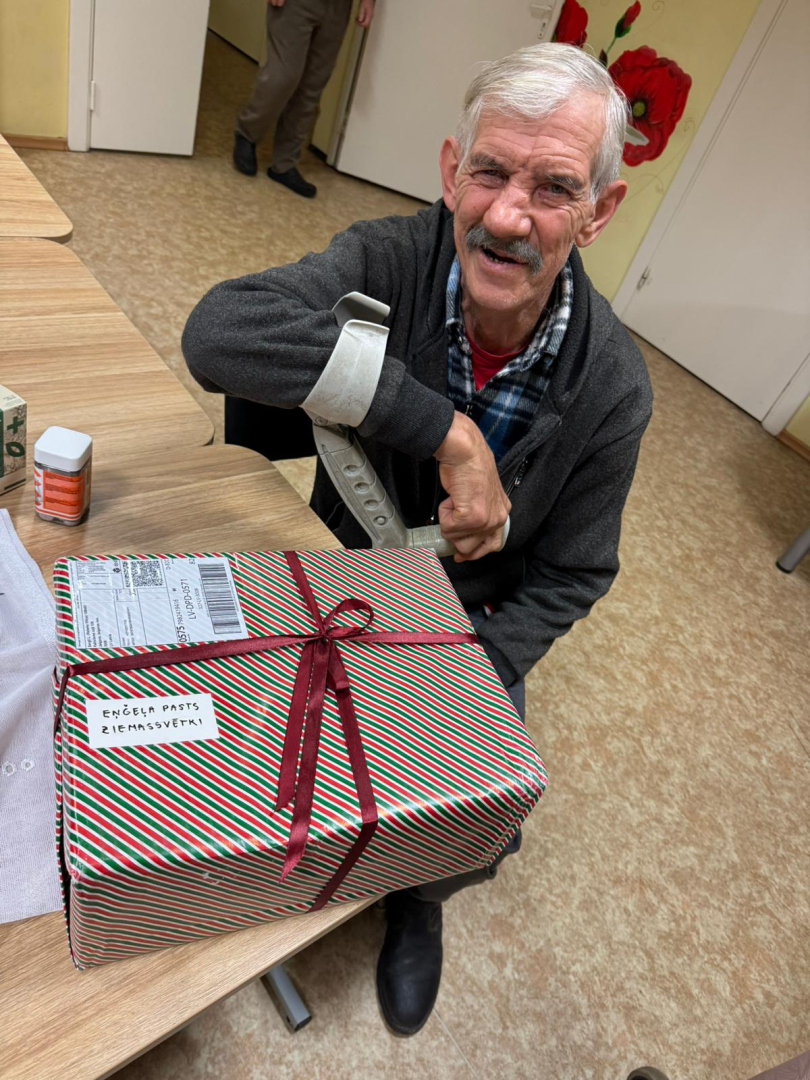 Smaidīgs iedzīvotājs ar dāvanu rokās