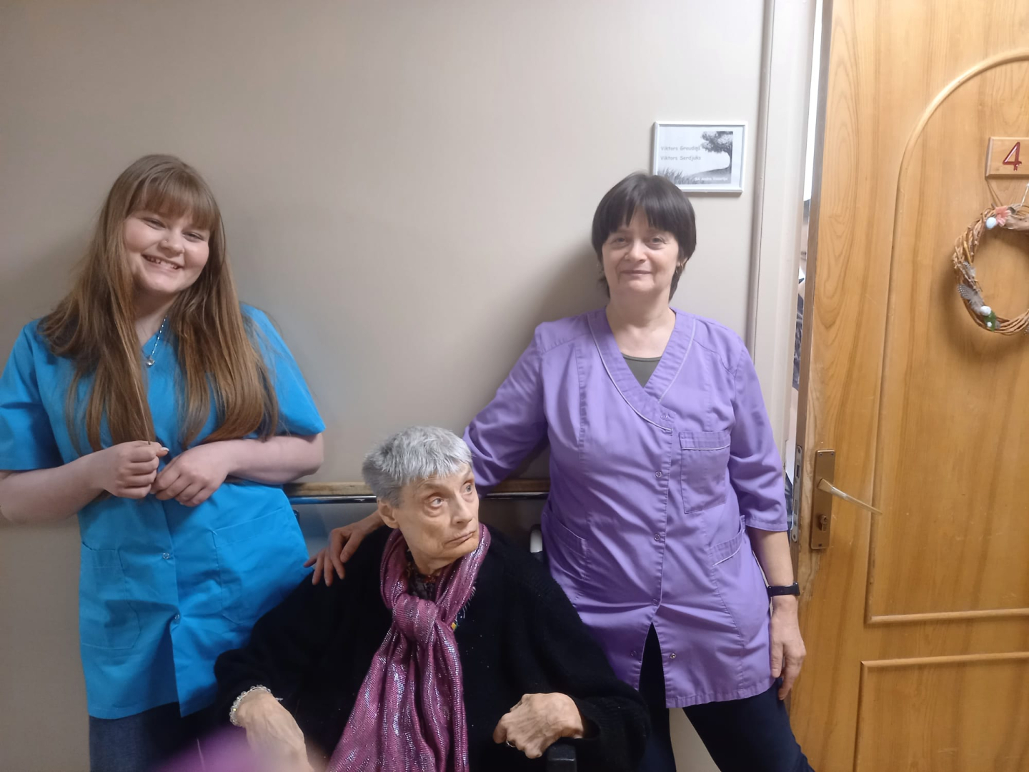 Smaidīga jauniete kopā ar iestādes darbinieci un iestādes iedzīvotāju