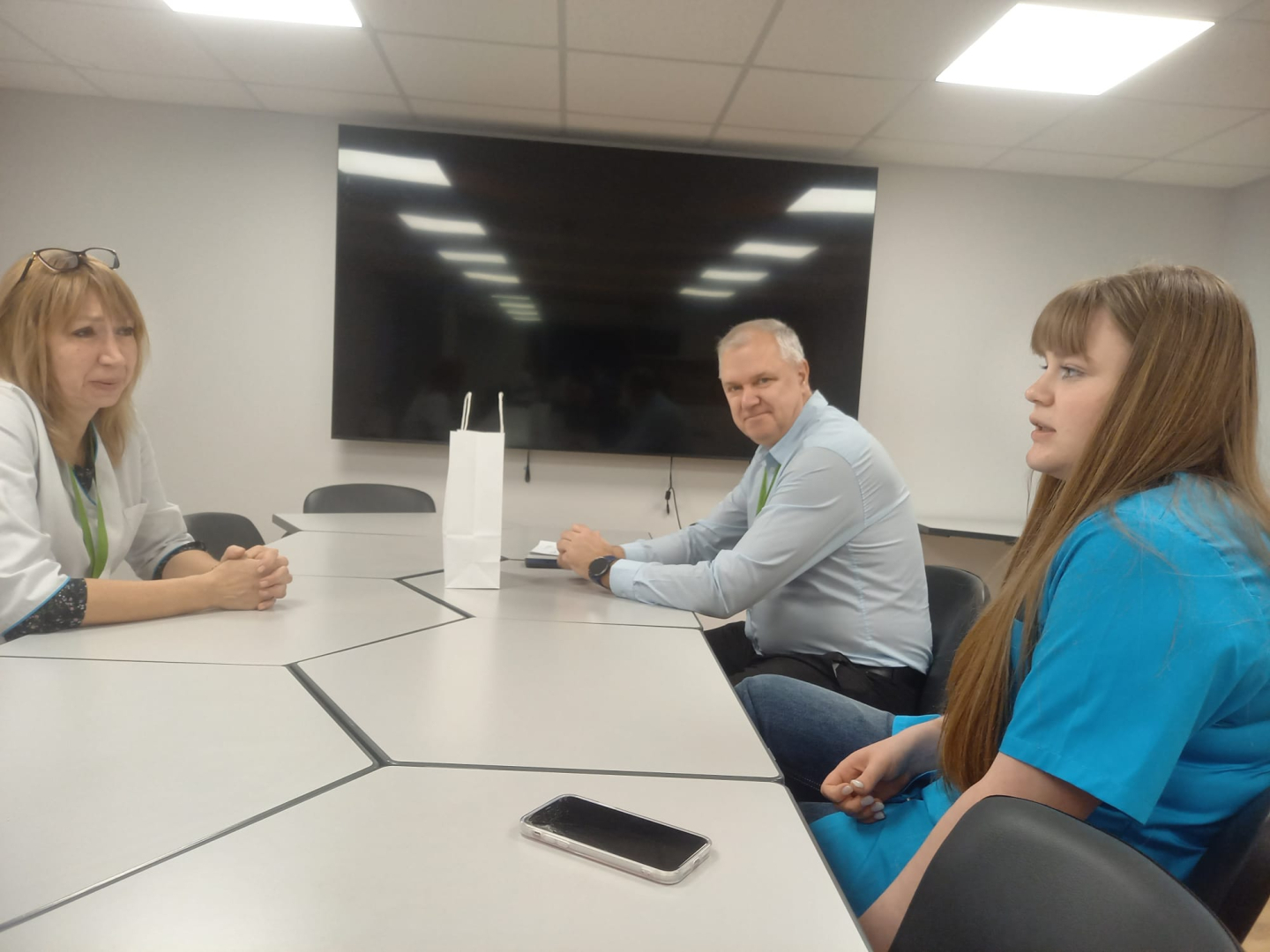 Jauniete ar filiāles darbinieci un vadītāju gaišā telpā sarunājas