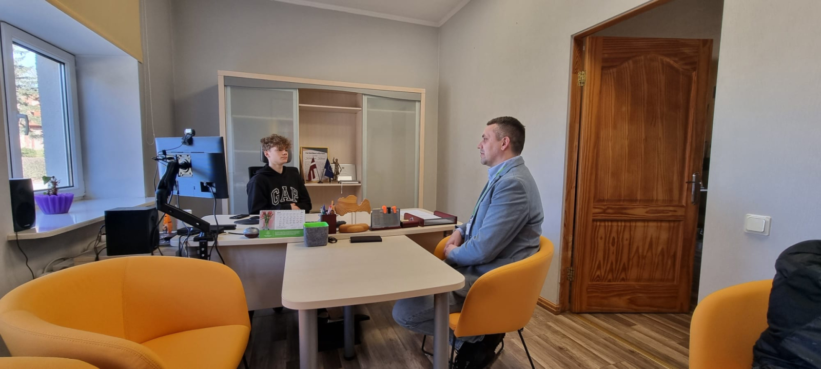 Kabinetā sēž divi cilvēki. Iestādes direktors un viņa ēna skolnieks