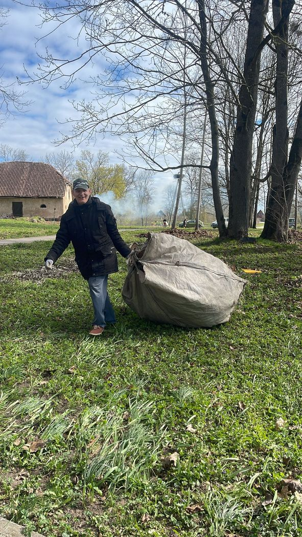 Cilvēks veic teritorijas uzkopšanas darbus. Nes lielu maisu