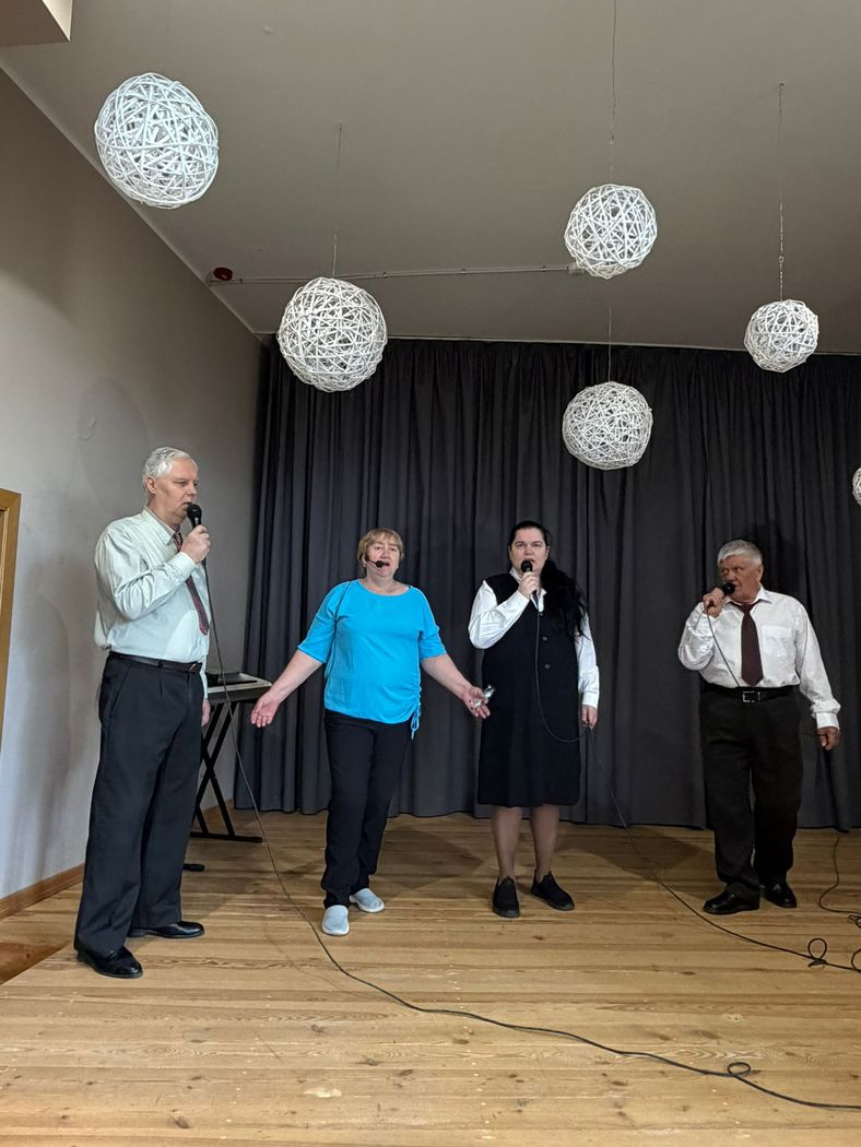 Uz skatuves ar mikrofoniem uzstājasčetri cilvēki