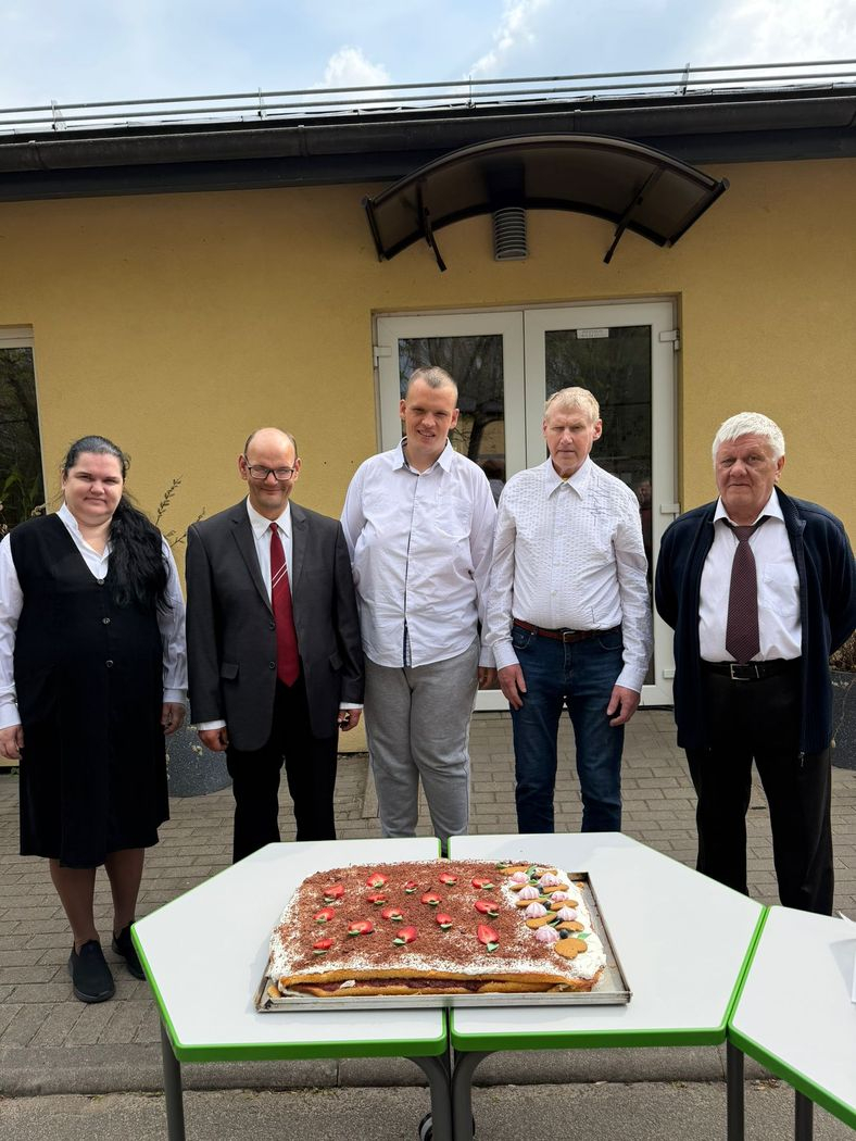 iedzīvotāji smaidīgi, viņiem priekšā uz galta svētku torte