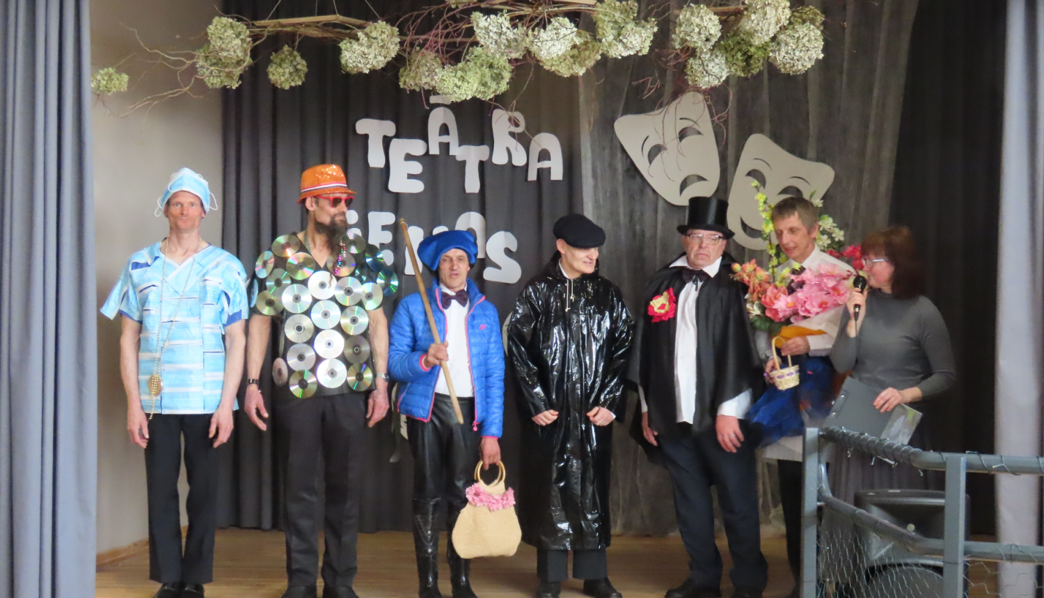 Teātra dienas skatuve uz kuras stāv tās dalībnieki košakos tērpos